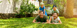 © ronstik - happy family with two children lying in the home backyard garden lawn and looking at camera. banner with copy space