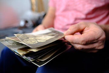 close-up of old male hands holding retro family photos of 1960-1965, vintage monochrome photographs in sepia color, genealogy concept, ancestral memory, family ties, childhood memories