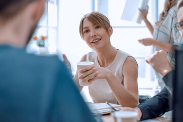 Poster - young business woman sitting at office Desk