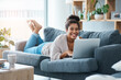 © Adene Sanchez/peopleimages.com - Im always happy when I get time to blog. Full length portrait of a happy young woman using her laptop while laying on the sofa at home.