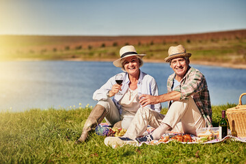 Sticker - Love keeps us young at heart. Shot of a happy senior couple drinking wine while enjoying a picnic outside.