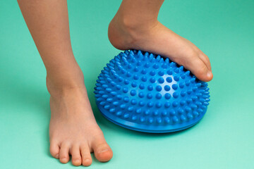 children's feet with a blue balancer on a light green background, treatment and prevention of flat feet, valgus deformity of the foot