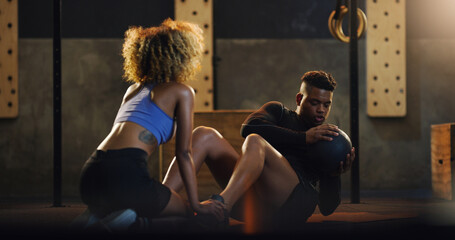 Poster - Building a stronger core with every twist. Shot of a young man doing russian twists with a weighted ball and the help of a trainer in a gym.
