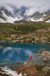 Hiking woman in red jacket standing at beautiful lake in mountains.