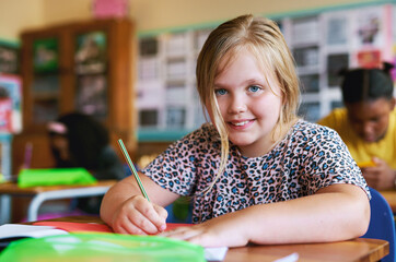 Sticker - Im always eager to learn. Shot of a young girl sitting in her classroom at school and writing in her workbook.