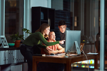 Wall Mural - The internet is there to make things easier. Shot of a group of designers looking at something on a computer while working late.