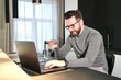 © Евгений Шемякин - Portrait of happy positive guy, young cheerful man is enjoying internet online shopping, purchasing on his laptop computer and holding credit bank card in hand, sitting at home, smiling, entering