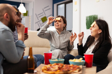 Wall Mural - Businesspeople playing charades game and having fun together at office party, using sticky notes on forehead for guessing activity. Man and women enjoying drinks after work hours.