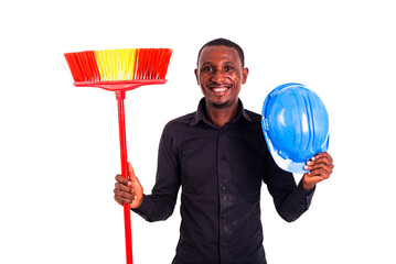 Wall Mural - young man engineer holding a broom and a safety helmet smiling.