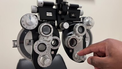 Poster - African American Man adjusting dials on phoropter used for eye examination or testing for eye glasses in ophthalmology, optometry, and optician offices