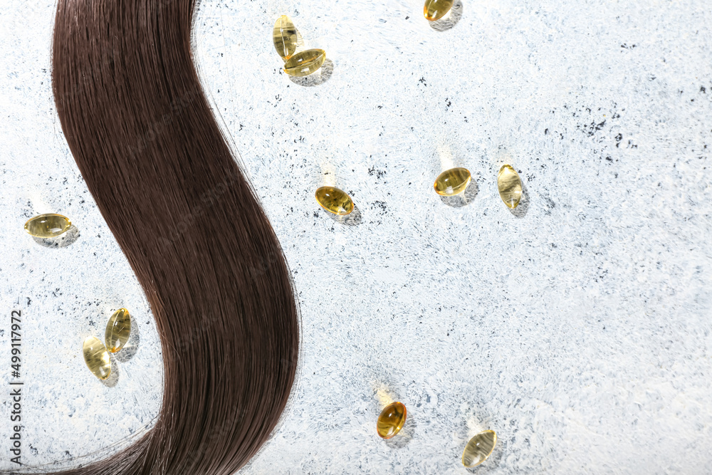 Brunette hair strand with pills on light background