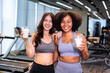 Asian and African American woman finishing workout and drinking protein milk shake vitamins after training. Bodybuilding. Healthy Friend lifestyle.