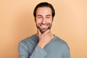 Poster - Photo of young cheerful man hand touch chin clever thoughtful salon isolated over beige color background