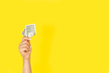Mano De Mujer Sosteiendo Un Billete Dolar Sobre Un Fondo Amarillo Liso Y Aislado. Vista De Frente. Copy Space