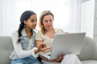 © Louis-Paul Photo - Adorable black teen daughter with mother sit on sofa at home with laptop