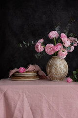 Fotomurales - Pink Ranunculus flowers on the pink tablecloth and dark wall, selective focus image