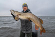 Success pike fishing. Happy fisherman with big fish trophy at boat