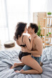 © LIGHTFIELD STUDIOS - side view of passionate woman in lace underwear seducing shirtless man in bedroom.