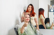 © finist_4 - Woman smiling with half shaved head in barber chair hairdresser taking photo.