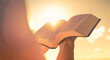 Person holding reading bible up to the sunlight