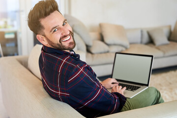 Poster - Winding down online. Shot of a relaxed young man using a laptop on the sofa at home.