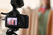 © Pixel-Shot - Young female clothes stylist recording video in studio, view on screen of modern video camera