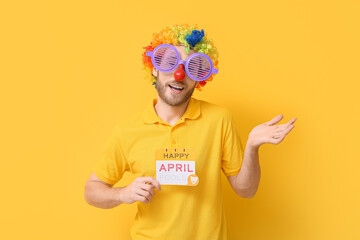 Poster - Funny young man in disguise and with card on yellow background. April fools' day celebration