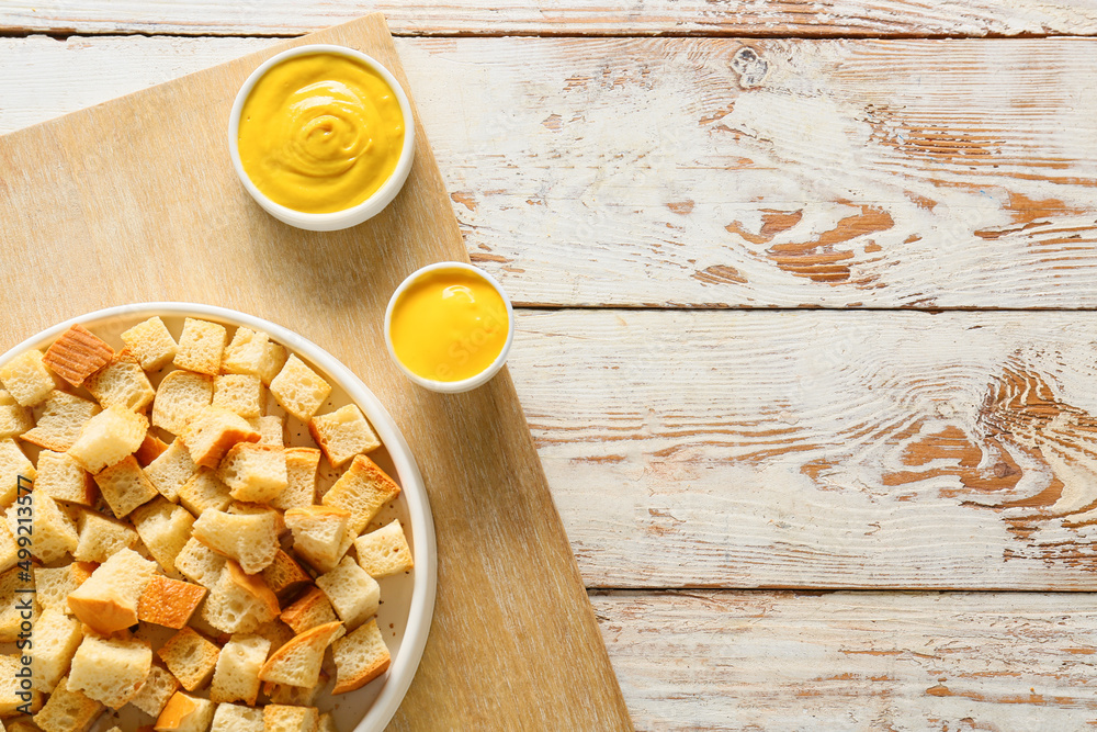 Bowl with croutons and sauces on light wooden background