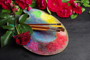 Canvas Print - Artist's palette, brushes and red roses on a dark background