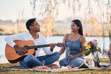 Sticker - This song goes out to my special lady. Shot of a young man playing a guitar while on a picnic with his girlfriend at a lakeside.