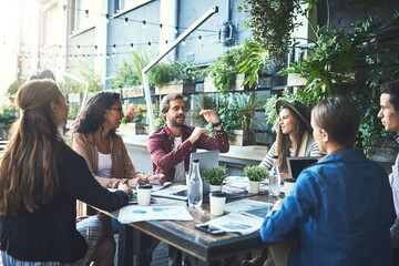 Sticker - Work outside the box. Shot of a group of designers having a meeting at a coffee shop.