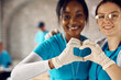 Close up of volunteers making heart shape of their hands while working at donation center.