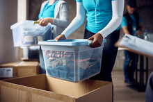 Unrecognizable Black Woman Packing Boxes Of Clothing While Volunteering At Donation Center.