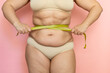 © Юля Бурмистрова - Cropped photo of naked after birth woman tummy in underwear, trying to lose weight. Holding and measuring her waistline by roulette tape belly, abdomen. Fat large sagging folds on stomach. Excess skin
