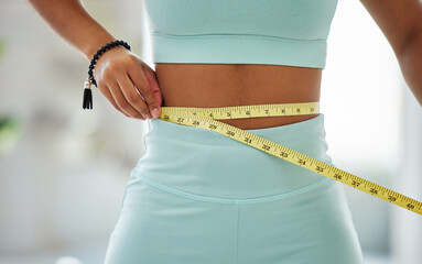 Poster - A few more inches and Id have reached my goal. Cropped shot of an unrecognisable woman standing alone and using a measuring tape around her waist in a yoga studio.