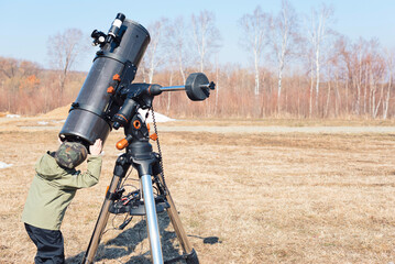 Wall Mural - child boy watching the sun through a telescope on a tripod at the observatory for observation of sta