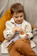 © Creative_Bird - Little adorable boy sitting on the couch at home, drinking milk with cookie. Fresh milk in glass, dairy healthy drink. Healthcare, source of calcium, lactose. Preschool child with casual clothing.