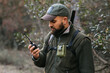 © Jordi Mora - Bearded male hunter using walkie talkie in forest