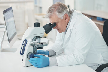 Sticker - Theres a lot to take note of when magnified. Shot of a mature scientist using a microscope in a lab.