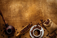 Coffee Mockup On Grunge Background Copy Space. Freshly Brewed Turkish Morning Espresso In White Cup, Scattered Beans, Vintage Cezve Pot And Vintage Sack, Spoon Top View