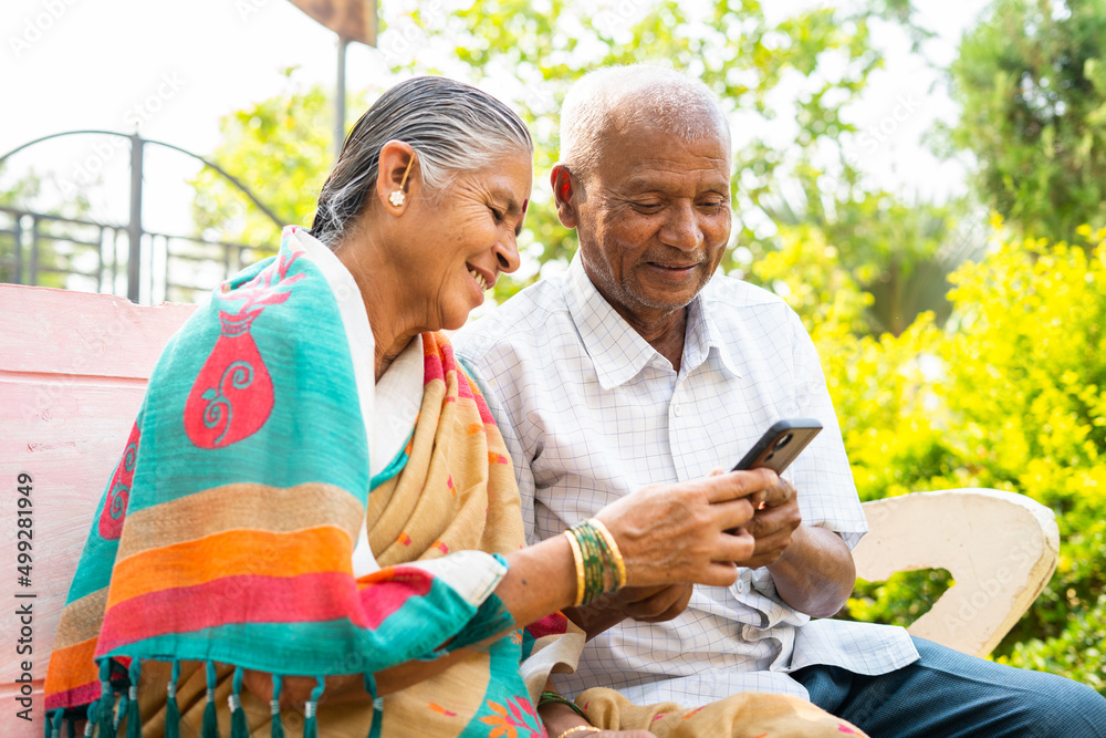 Senior couple using mobile phone while sitting on park - concept of ...