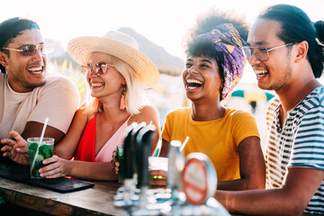 Wall Mural - Happy young people drinking at beach cocktail bar - Multiracial friends hanging out enjoying summer vacation - Summertime holidays with guys and girls laughing outside