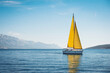 canvas print picture - White yacht with yellow sails in the sea against a background of blue sky and mountains