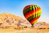 Fototapeta Góry - View of colorful hot air balloons with passengers landing on the plane at Valley of The Kings in the morning, Luxor, Upper Egypt.