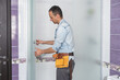 © Angelov - Workers are installing a silicone gasket seal on the glass door of the shower enclosure.
