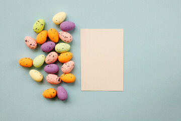 Wall Mural - Happy Easter composition with Easter colored eggs and paper blank on a pastel blue background. Flat lay, top view, copy space.