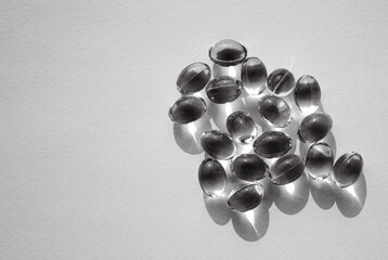 Pads scattered on the white surface. Close-up view of omega 3 capsules. Black and white image.