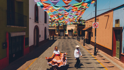 Wall Mural - Aerial photo of dancers of typical Mexican dances from the downtown region, doing their performance in the street adorned with bandanas.