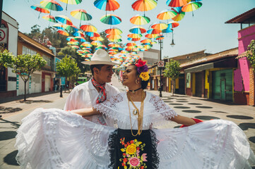 Dancers of typical Mexican dances from the region of Veracruz, Mexico, doing their performance in the street adorned with colored umbrellas.