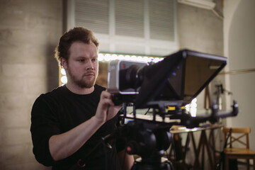 Director of photography with a camera in his hands on the set. Professional videographer at work on filming a movie, commercial or TV series.